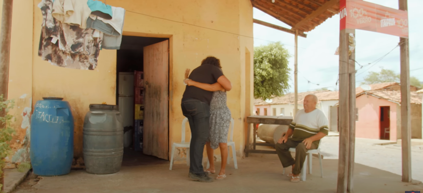 A person hugging another person outside a building
Description automatically generated